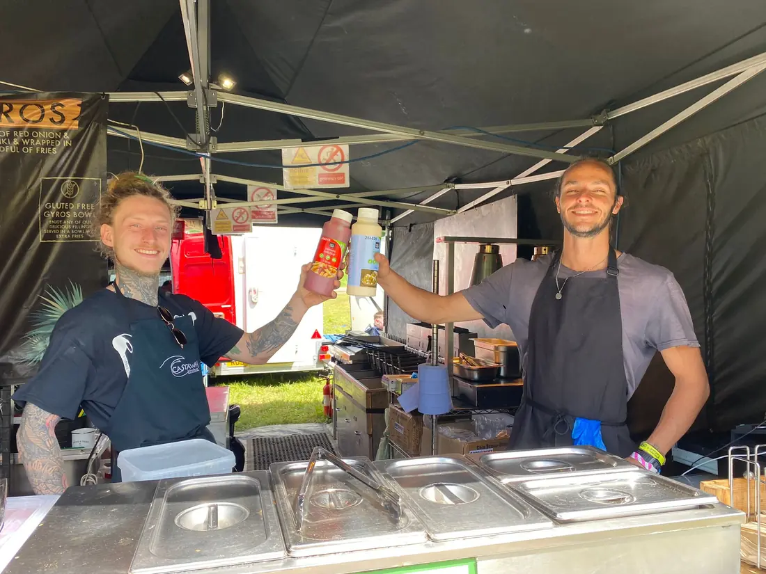 Two Castaway Kitchen staff toasting with sauce bottles in the unit