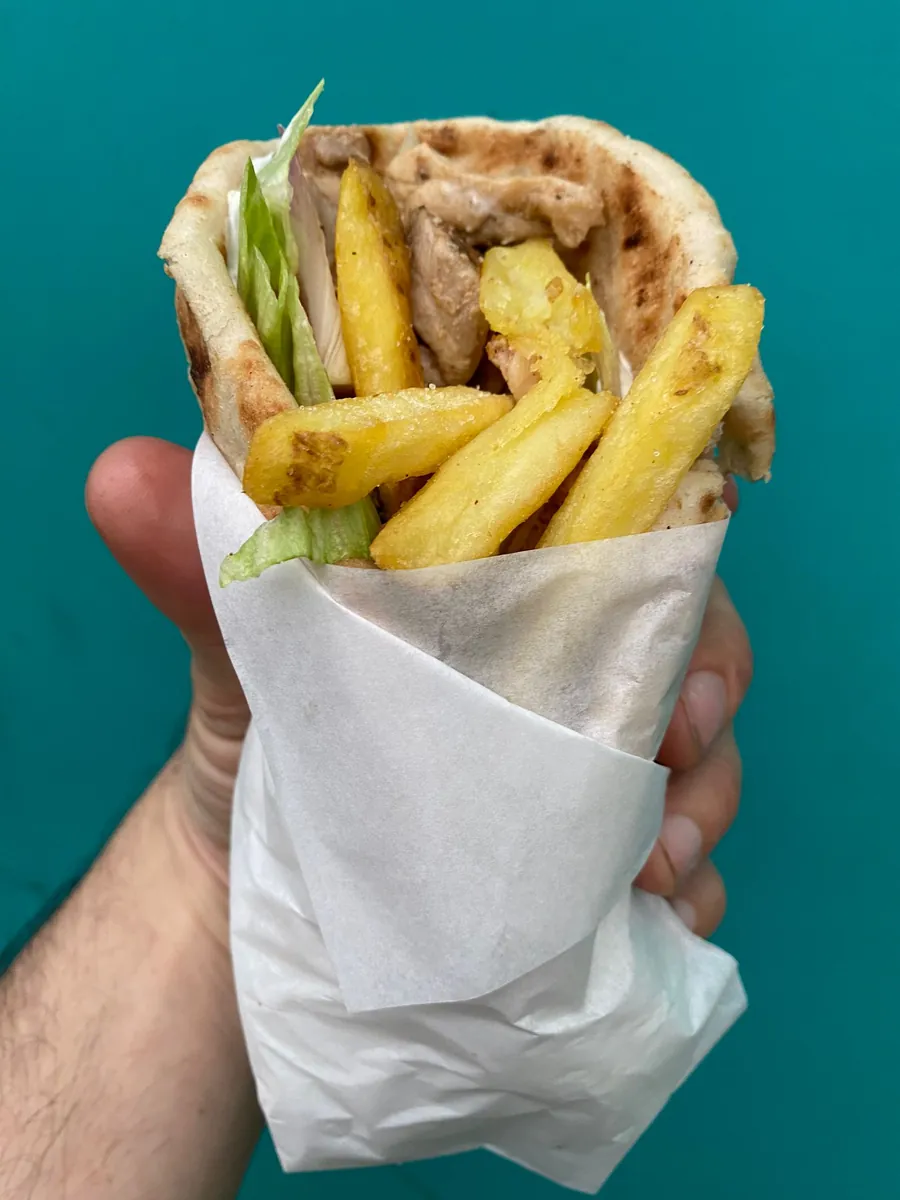 A chicken gyros loaded with fries, fresh salad and tzatziki